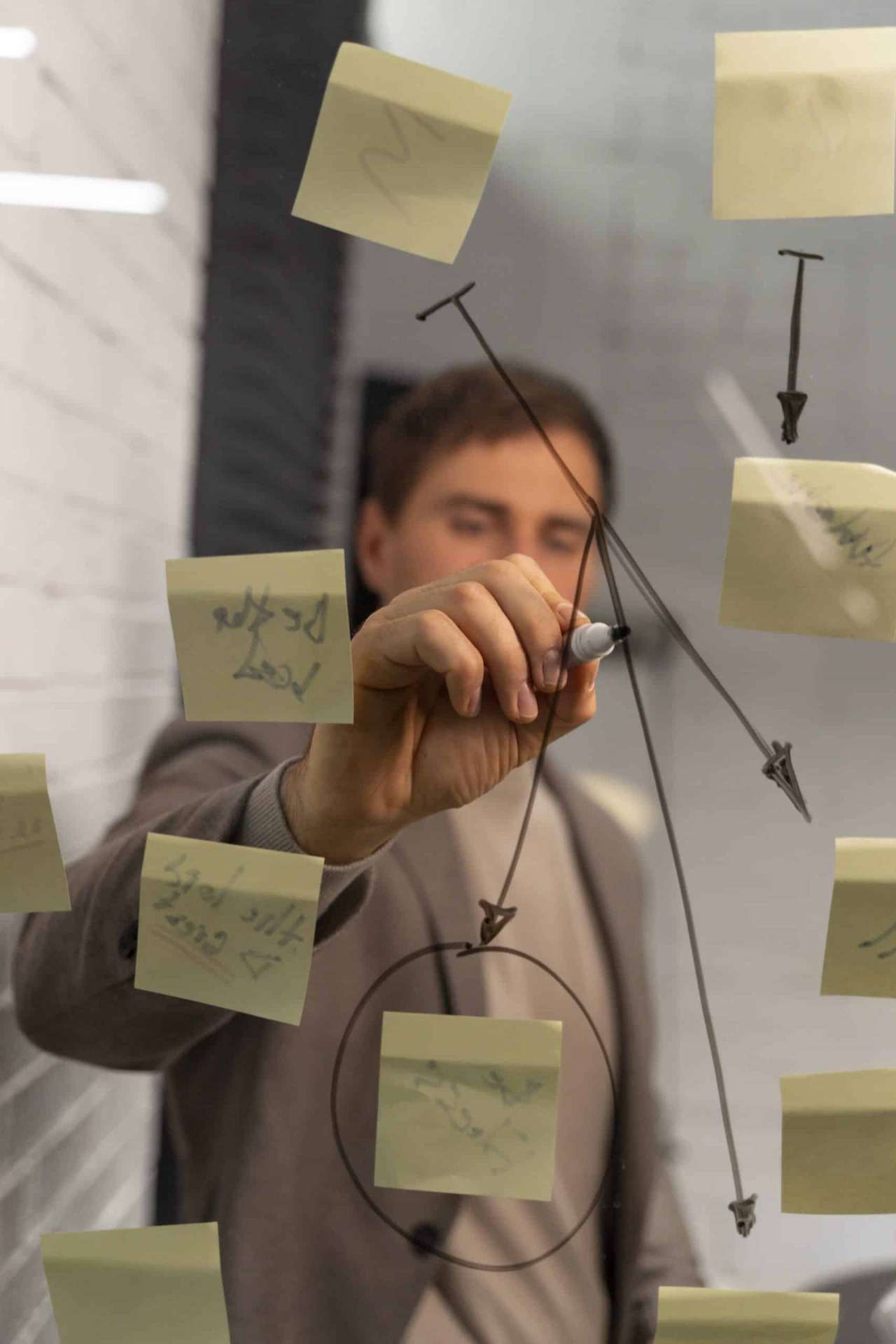 Strateeg werkt aan plan met post-its op glas